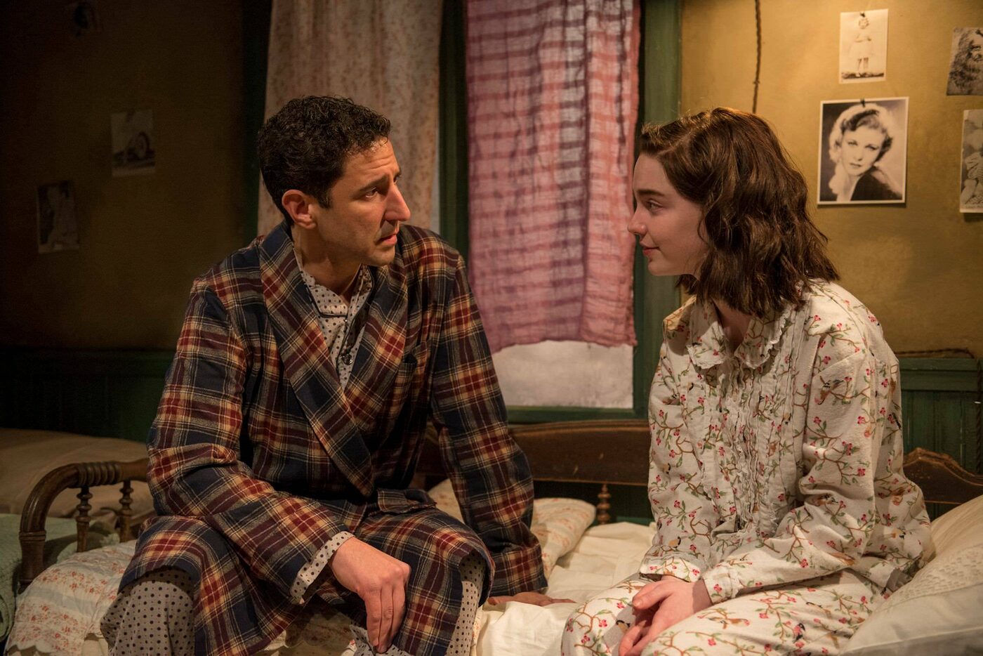 A man in a plaid robe sits on a bed beside a young woman in The Diary of Anne Frank