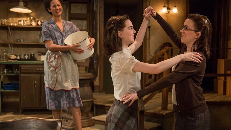 A woman in an apron and two young women dancing in the attic kitchen