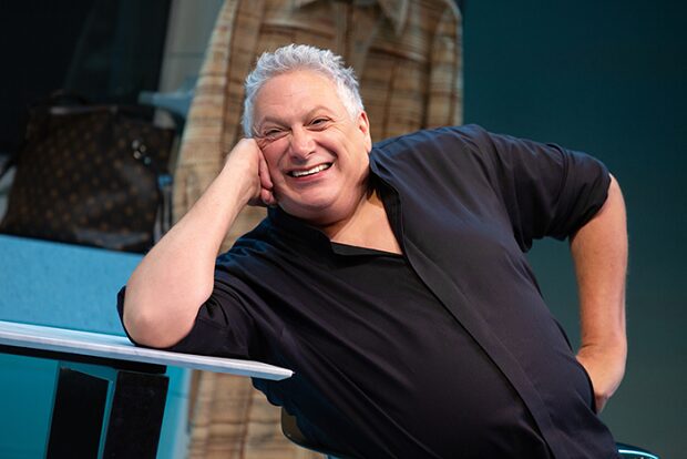 Harvey Fierstein as Bella Abzug leaning on a table and laughing in Bella Bella