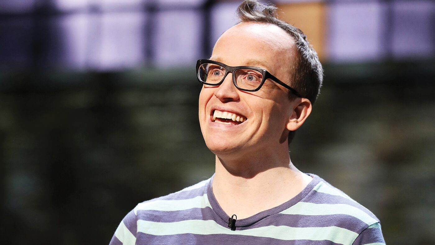 Chris Gethard smiling on stage in a striped shirt