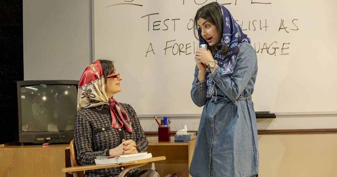 A teacher at the whiteboard and a student holding a microphone in an English-language classroom