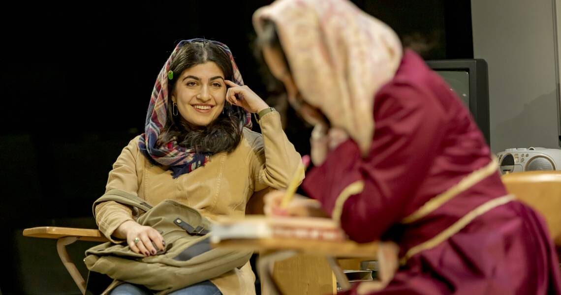Two young women in headscarves seated at classroom desks