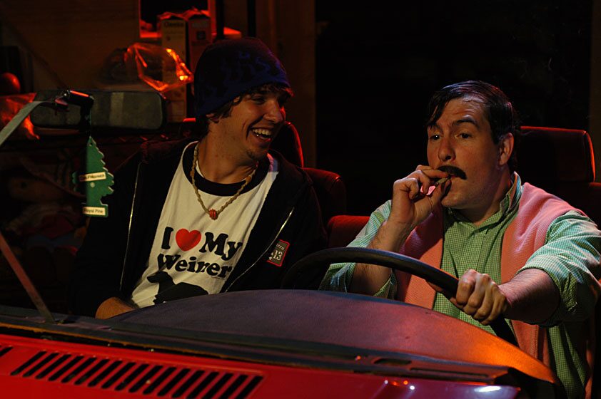 Two men laughing together in a car in Fuddy Meers