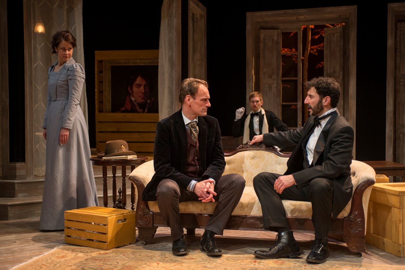 Four characters on a sofa in a period drawing room in Hedda Gabler