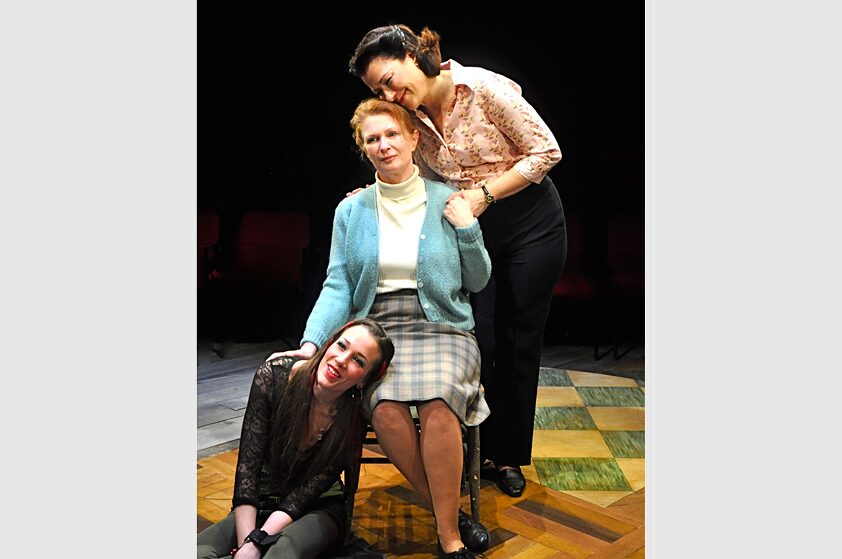 Three generations of women gathered together, smiling, in Little Gem
