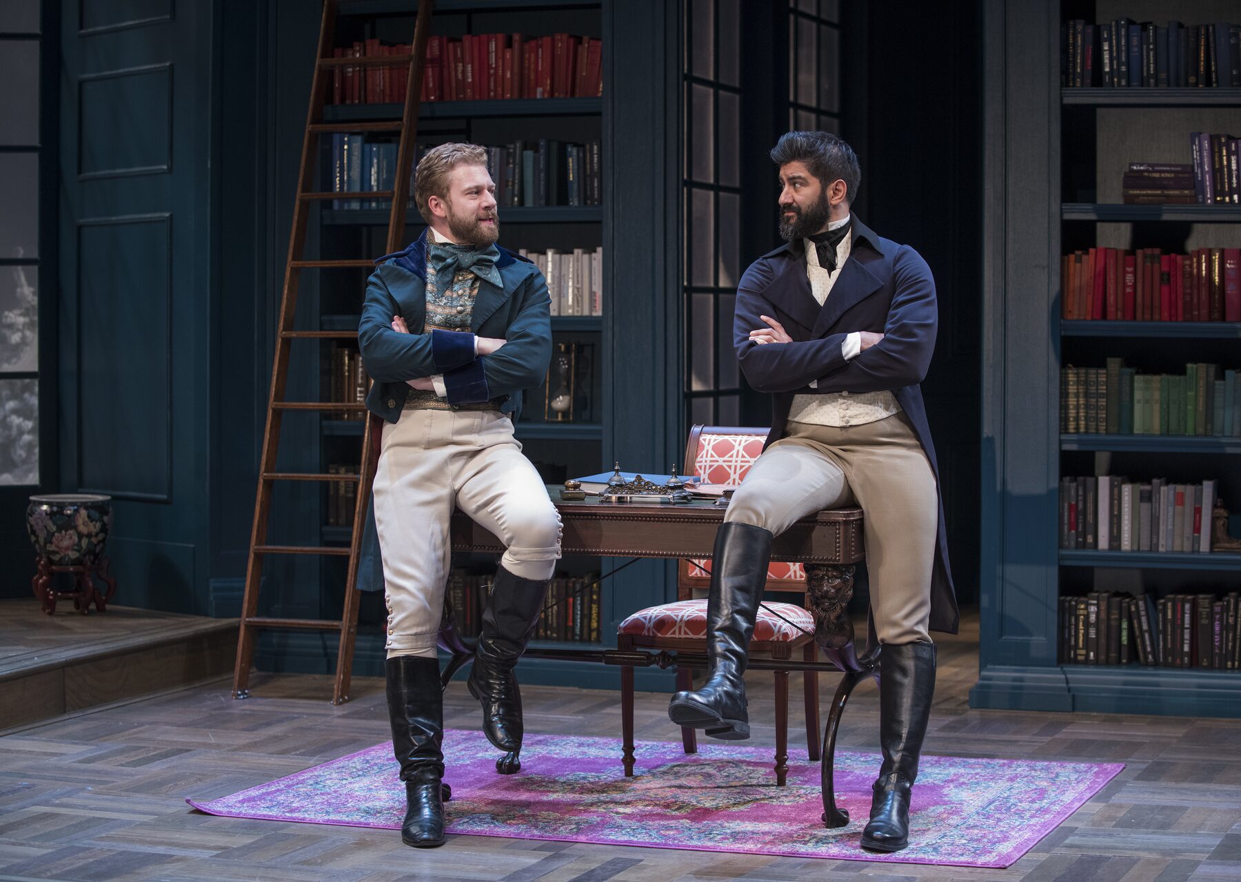 Two gentlemen in Regency dress lean on a library table