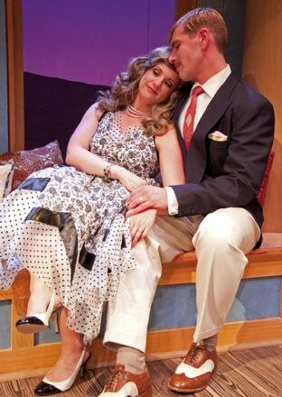 A man in a plaid dressing gown seated beside a woman in a starred dress