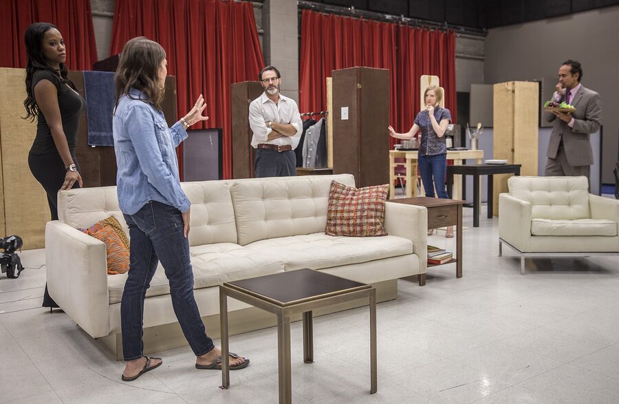 Kimberly Senior directing two actors in the Disgraced living-room set as the rest of the cast looks on
