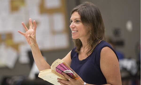 Kimberly Senior smiling and gesturing with an open script in hand during a Disgraced rehearsal