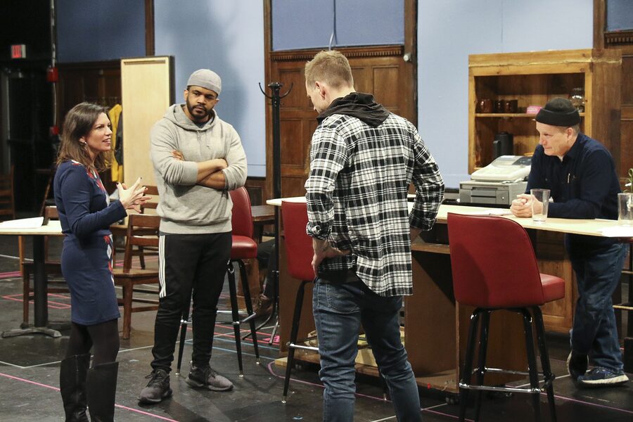 Kimberly Senior talking through a scene with two actors on the bar set of Sweat