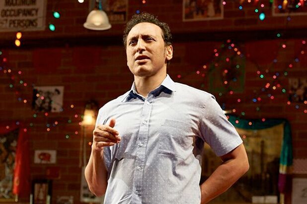 Aasif Mandvi performing in front of the brick-walled restaurant set of Sakina&rsquo;s Restaurant