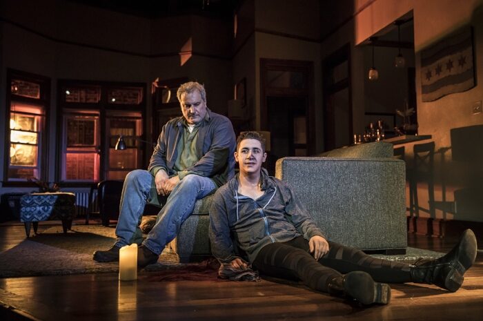 Men seated on the floor in a living room lit by candles in Support Group for Men