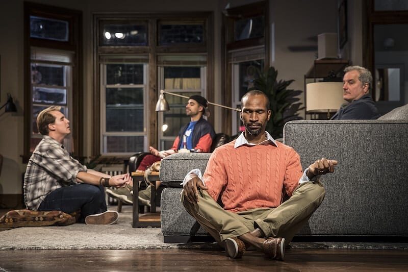 A man sitting cross-legged in the middle of the group in Support Group for Men