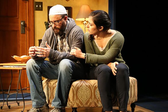 A bearded man in a prayer cap and a woman seated together on a bench in The Who & The What
