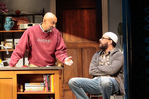 A father in a Harvard sweatshirt confronts a bearded man in the kitchen of The Who & The What