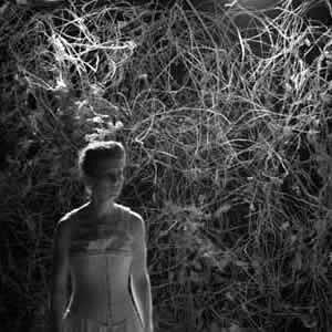 An actor onstage against a tangled branch backdrop in Three Sisters